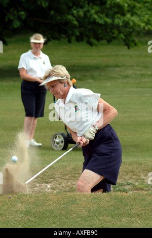 Signora golfista di blasti fuori del bunker di sabbia a Andover Golf Club Inghilterra Hampshire REGNO UNITO Foto Stock