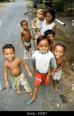 Bambini rush per accogliere i visitatori nella piccola città costiera di Amed Bali Indonesia Foto Stock