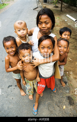 Bambini rush per accogliere i visitatori nella piccola città costiera di Amed Bali Indonesia Foto Stock