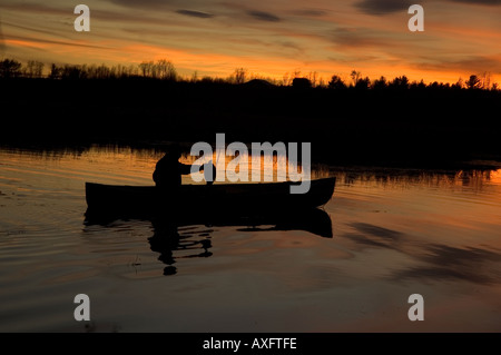 Un cacciatore di anatre riprende il suo decoy al tramonto dopo una giornata di caccia. Foto Stock