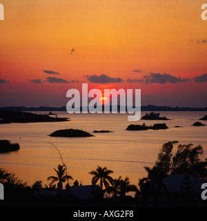 Rosso e arancione tramonto su numerose piccole isole stagliano in grande suono Bermuda impostato sul mare calmo con palme primo piano Foto Stock