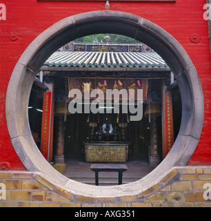 Vista del tempio Cinese interno attraverso una circolare grande porta la luna porta impostato in un dipinto di rosso la parete del Tempio A-Ma a Macao Foto Stock