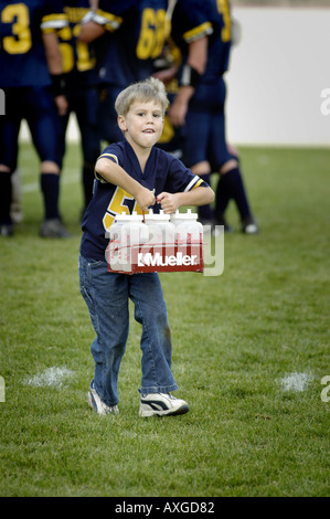 Ragazzo di 7 anni serve come un ragazzo di acqua helper durante una alta scuola calcio contest Foto Stock