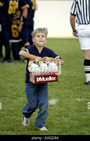 Ragazzo di 7 anni serve come un ragazzo di acqua helper durante una alta scuola calcio contest Foto Stock