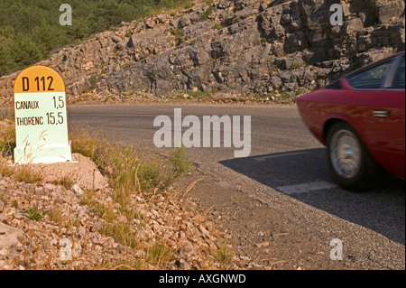 Classic car passando chilometro post nelle Alpi francesi Foto Stock