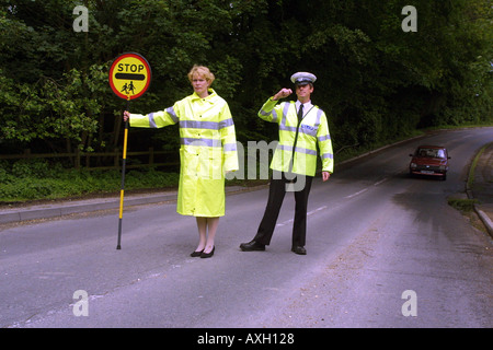 Attraversamento Scuola patrol donna con il segnale di arresto e funzionario di polizia sulla strada. Inghilterra REGNO UNITO unione Foto Stock