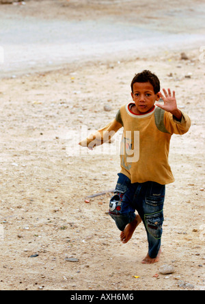 Un giovane ragazzo tunisino corre per le penne e i libri di scuola che è gettato dalla Lucertola rossa treno, Tunisia. Foto Stock