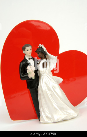 Coppia di sposi figurine e cuore rosso, immagine simbolica di nazionalità mista / mixed-gara matrimonio Foto Stock