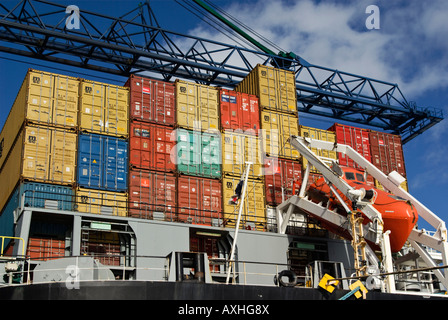 Pile di contenitori sul ponte di poppa di una nave portacontainer con un braccio della gru overhead. Foto Stock