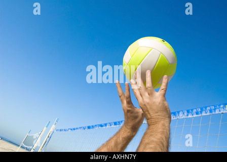 Un giocatore di volleyball lob una palla durante un gioco in spiaggia Foto Stock
