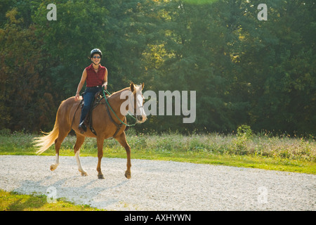 ILLINOIS Donna a cavallo sulla ghiaia sentiero ricreativo presso Glen Raven Forest Preserve indossando il casco Foto Stock