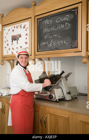 Butcher's Assistant in Shop Wearing Red Apron  W Irvine Butchers Blairgowrie, Scozia Regno Unito Foto Stock