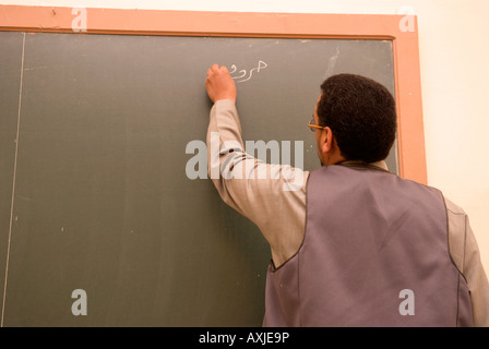 Insegnante scrivere sulla lavagna durante l'istruzione degli adulti classe in arabo a islamica di arti e mestieri Scuola Tripoli in Libia Foto Stock