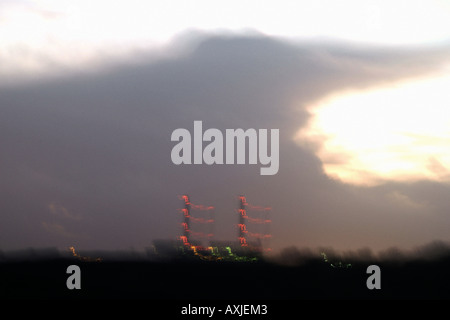 Nuvole scure con fumaioli illuminato da luci rosse al tramonto all'orizzonte Foto Stock