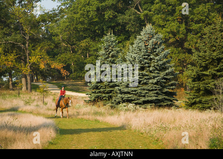 ILLINOIS Donna di equitazione su erba rasata trail a Glen Raven Forest Preserve parallelamente alla ghiaia percorso ricreativo Foto Stock