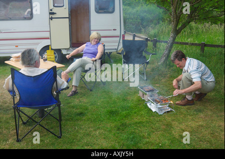 Tre i villeggianti avente un barbecue al di fuori di una roulotte Northumberland REGNO UNITO Foto Stock