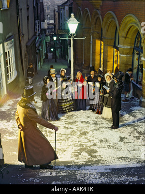 Coro di otto persone vestite come cantanti Vittoriano di notte sotto il vecchio lampione a fasi di Natale a Bristol REGNO UNITO Foto Stock