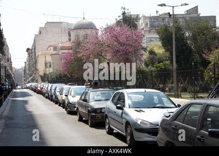 Auto parcheggiate su Filonos St con viola primavera sbocciano i fiori e il Greco Orhtodox chiesa nel porto del Pireo o Pireo ad Atene in Grecia Foto Stock