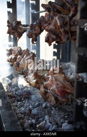 Porzioni di carne di pecora essendo barbeque alla griglia su uno sputo in Kalivia Attica o Atiki Grecia Foto Stock