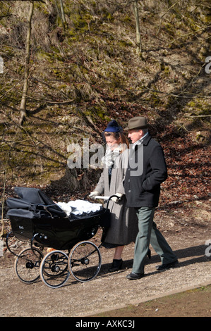 L uomo e la donna spingendo un nero pram con baby Crich forties weekend Peak District Derbyshire England Regno Unito Foto Stock