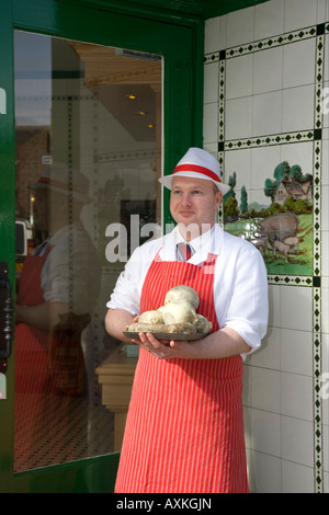 Macellaio in piedi all'ingresso del negozio che indossa il Red Apron  W Irvine Butchers Blairgowrie, Scozia, Regno Unito Foto Stock