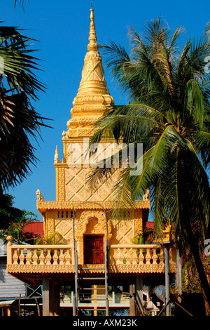 Cambogia ,Lago Tonle Sap , villaggio tempio Buddista pagoda dorata su palafitte circondata da palme e cielo blu Foto Stock