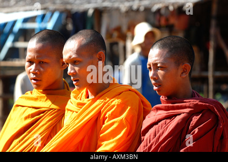 Cambogia ,Lago Tonle Sap , villaggio scena di giovani monaci in giallo, arancione e rosso abitudini Elemosinare il cibo Foto Stock
