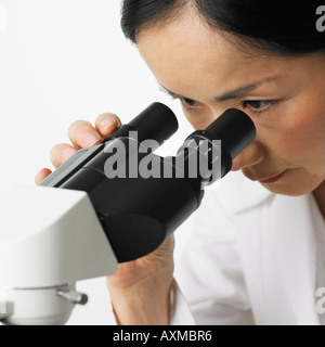Close up della donna che guarda nel microscopio Foto Stock
