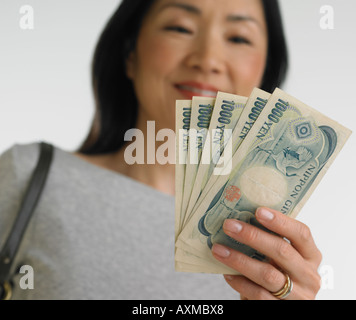 Basso angolo di visione della donna asiatica azienda denaro giapponese Foto Stock