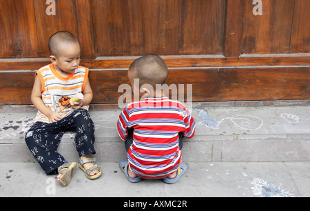 Due giovani ragazzi cinesi a giocare sul marciapiede Foto Stock