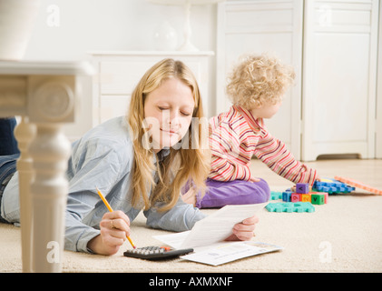 La madre lavora sulla calcolatrice mentre il bambino gioca Foto Stock