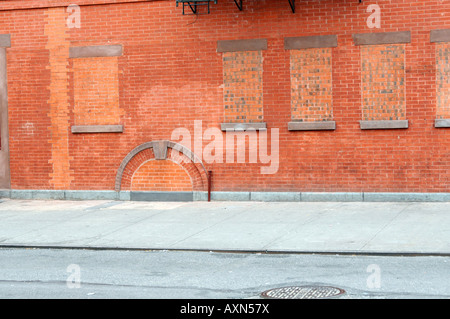 Muro di mattoni con le vecchie finestre e porta nel seminterrato riempito con mattoni Foto Stock