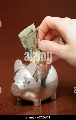 Argento piggybank con un bill inceppato nel suo retro, close-up Foto Stock