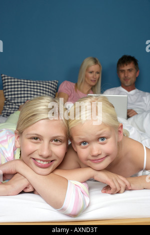 Due ragazze bionda giacente sorridente nel letto dei genitori, il fuoco selettivo, close-up Foto Stock