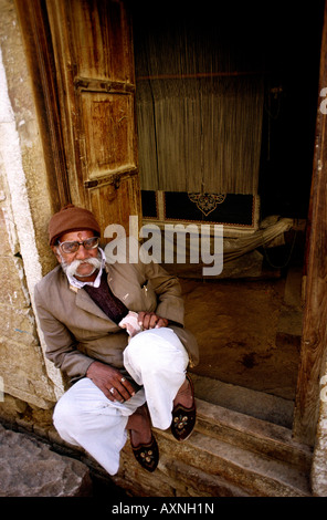 India Rajasthan artigianato Jaisalmer vecchio uomo seduto nella porta della tessitura dei tappeti workshop Foto Stock