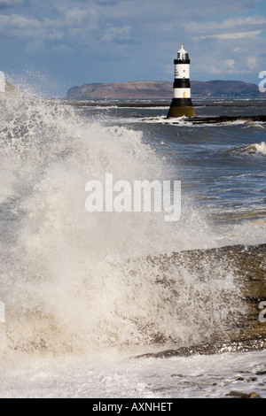 Mare mosso durante la wild vento tempestoso Penmon meteo faro grandi onde in primo piano sulla costa rocciosa Penmon punto isola di Anglesey nel Galles REGNO UNITO Foto Stock