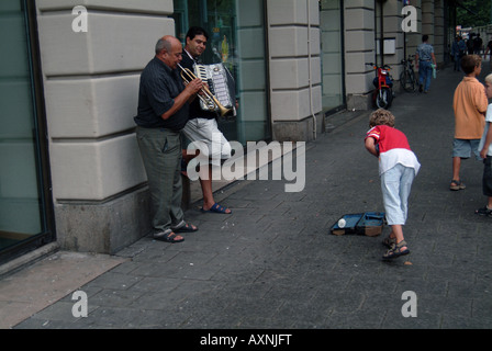 Una strada ad Amsterdam con moto o biciclette bloccato a lungo di essa e musicisti di strada la riproduzione Foto Stock