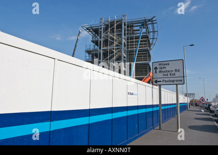 Blu e bianco scherma intorno al sito in costruzione accanto a OCCUPATO A27 Strada Principale Foto Stock