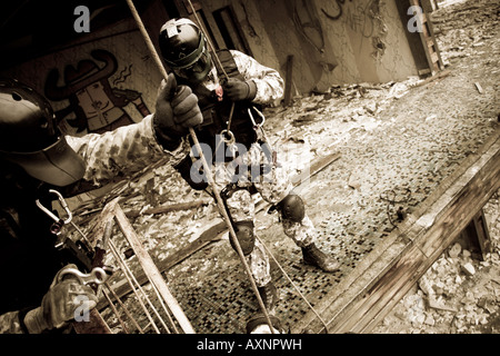 Due anti-terroristiche ufficiali si stanno preparando per la corda verso il basso durante il corso di formazione azione di salvataggio in un edificio devastato. Foto Stock