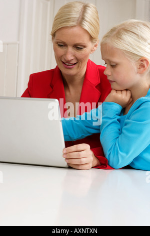 Ragazza bionda è seduto accanto a sua madre dietro un laptop, close-up Foto Stock