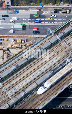 Vista Aeiral di treni che transitano sulle vie e le vetture e autocarri guida su strada sotto nella sezione di Shiodome di Tokyo, Giappone Foto Stock