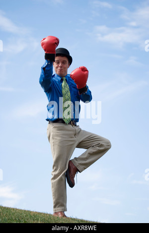 Uomo che indossa guantoni da pugilato e derby hat in piedi su una gamba Foto Stock