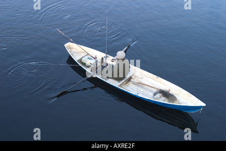 Pescatore finlandese che canta e traina da barche a remi/skiff al fiume Oulujoki, Finlandia Foto Stock