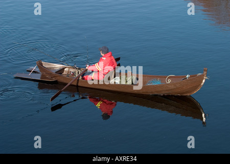 Pescatore finlandese che traina utilizzando una tradizionale barca a remi in legno / skiff presso il fiume Oulujoki, Finlandia Foto Stock