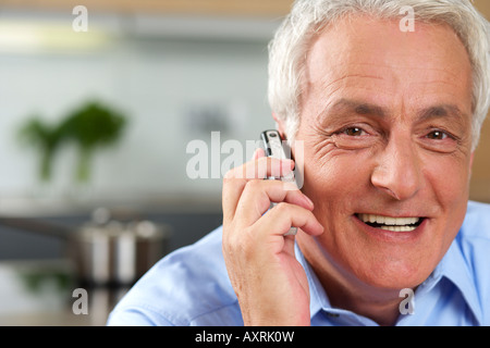 Grey-haired man è utilizzando il suo telefono cellulare, sorridente Foto Stock