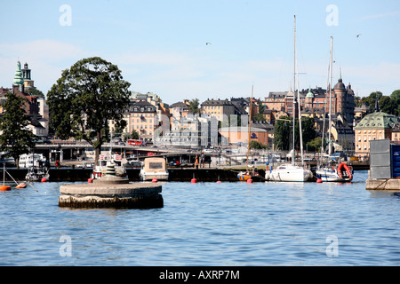 Un molo con piccole barche ormeggiate, città in background Foto Stock