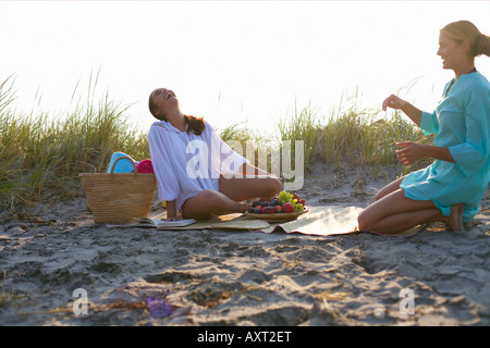 Due giovani donne aventi un picnic in spiaggia Foto Stock