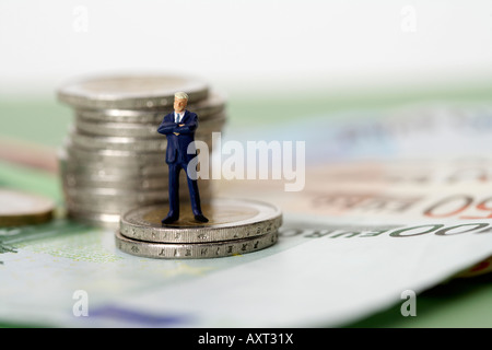 Imprenditore figurina in piedi su una pila di monete Foto Stock