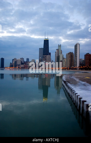 Il John Hancock Building si riflette nelle calme acque del lago Michigan all'inizio in una fredda mattina di febbraio. Foto Stock