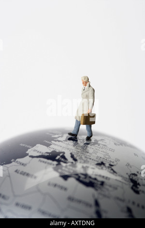 Imprenditore figurina con valigetta camminando sul globo terrestre Foto Stock